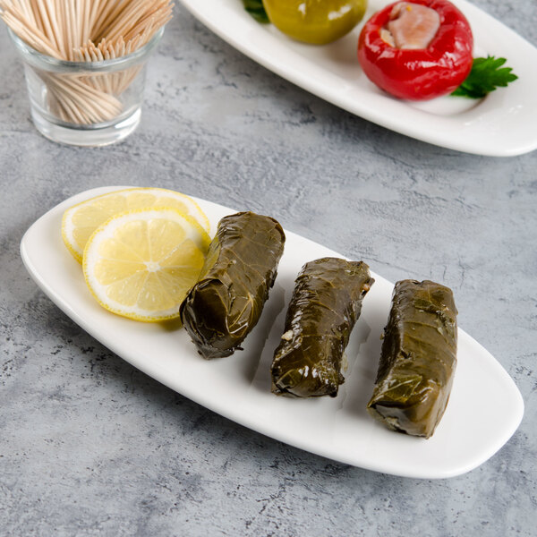 A Villeroy & Boch white oval porcelain platter with stuffed grape leaves and lemon slices on it.