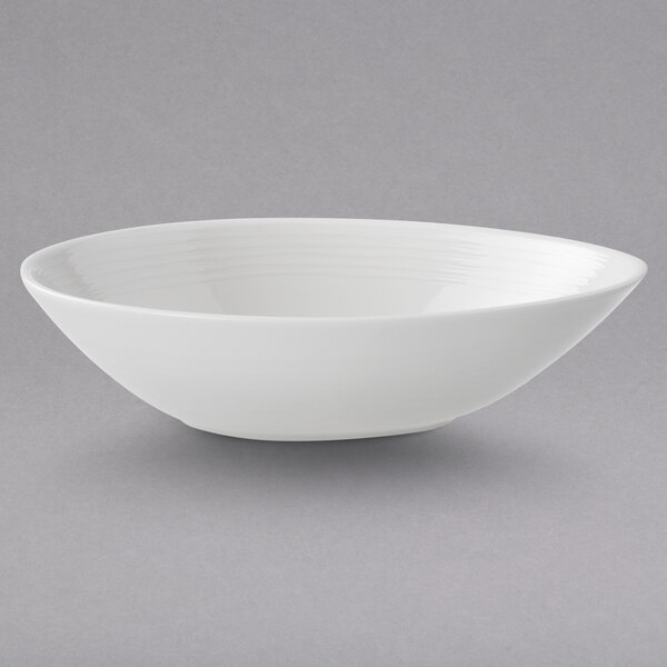 A white Villeroy & Boch porcelain oval bowl with a curved edge on a gray surface.