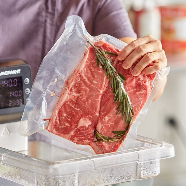 A person holding a VacPak-It 10" x 10" chamber vacuum packaging bag of meat on a counter.