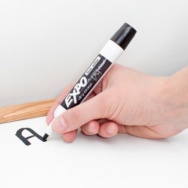 A hand holding a black Expo dry erase marker.