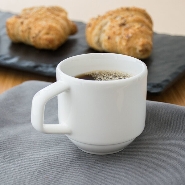 A white Villeroy & Boch stackable cup of coffee and croissants on a table.
