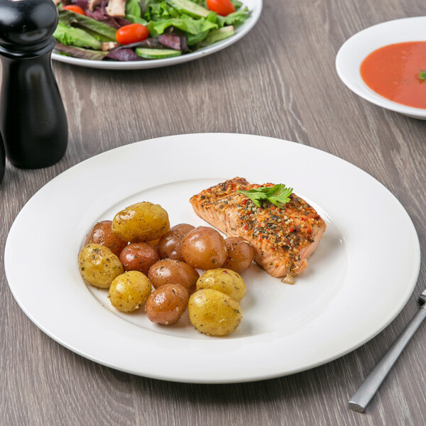 A Villeroy & Boch white porcelain plate with salmon and potatoes on a table.