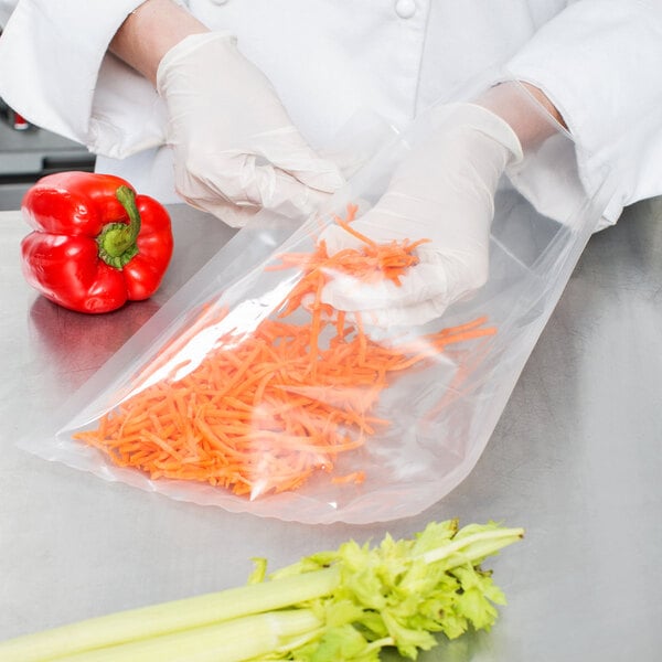 A person in white gloves putting carrots into a VacPak-It chamber vacuum packaging bag.