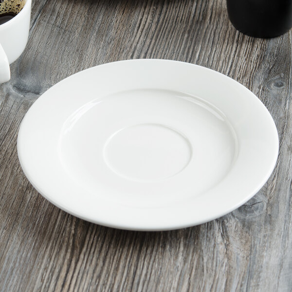 A Villeroy & Boch white porcelain saucer on a wood table.