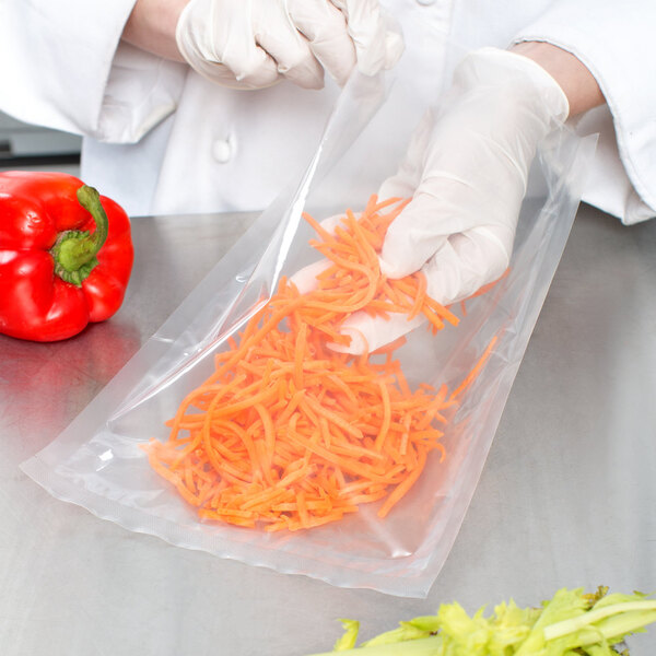 A person in white gloves using a VacPak-It plastic bag to hold shredded carrots.