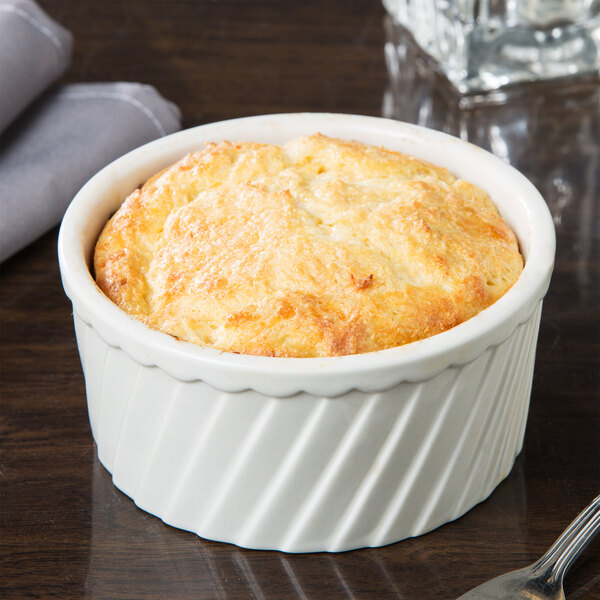 A white fluted souffle bowl filled with food.