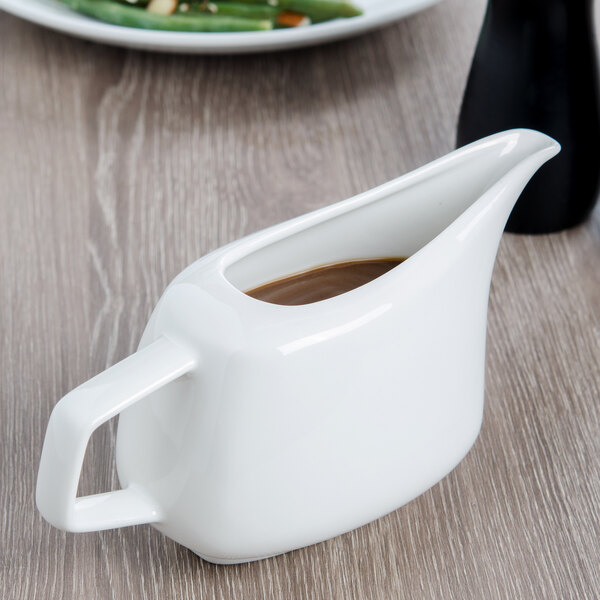A white Villeroy & Boch porcelain sauceboat on a wood surface.