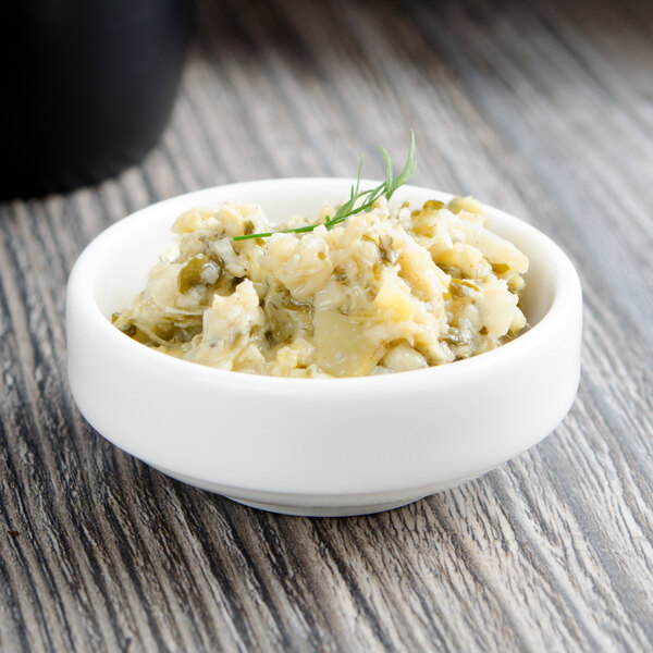 A Villeroy & Boch white porcelain bowl filled with mashed potatoes with dill and parsley on a table.