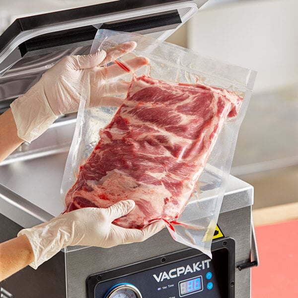 A person in gloves using a VacPak-It chamber vacuum packaging bag to hold a piece of meat.