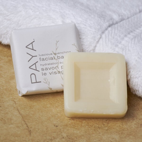 A PAYA Orange and Papaya facial bar of soap next to a white towel.