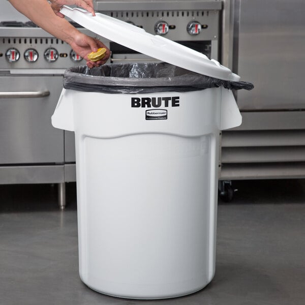 A person opening a white Rubbermaid BRUTE trash can.