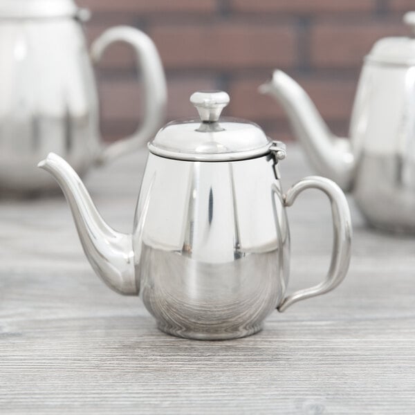 A mirror-finished stainless steel Vollrath Orion teapot on a table.