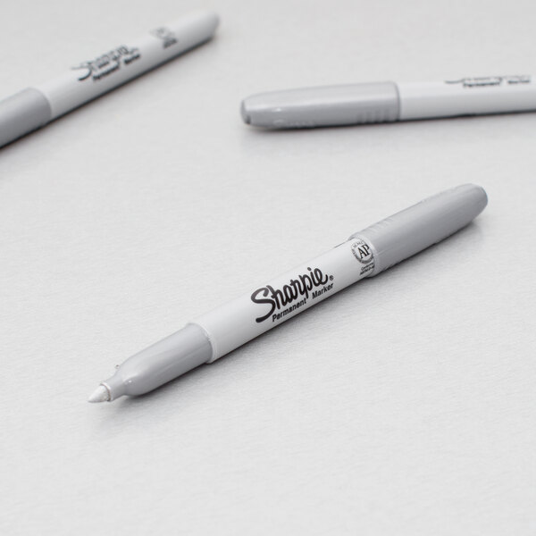 A close up of three Sharpie Metallic Silver markers with white and grey writing on them.