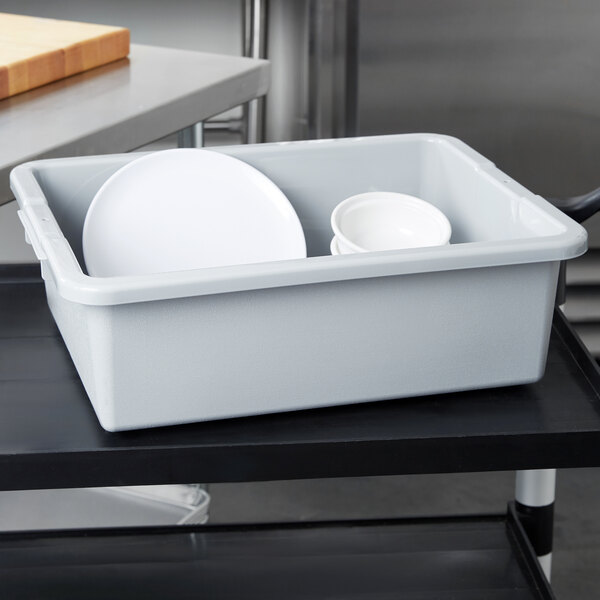 A gray Rubbermaid high density polyethylene bus tub on a counter with white dishes inside.