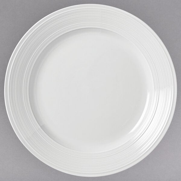 A close-up of a Libbey Galileo Lunar Bright white porcelain plate with a circular design.