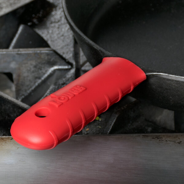 A red Lodge silicone handle holder on a black pan handle.