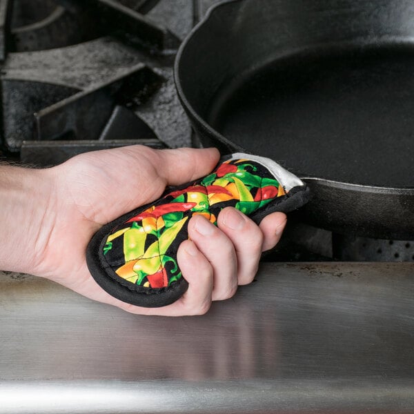 A hand holding a Lodge chili pepper handle holder on a hot pot.