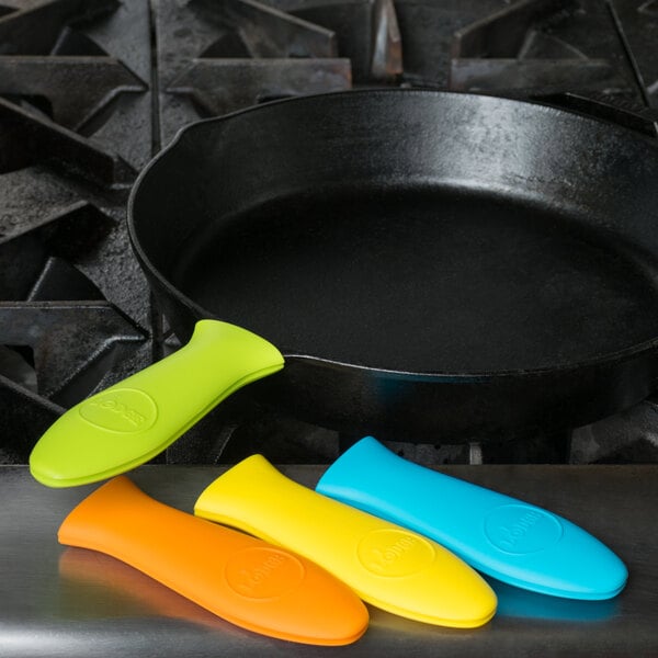 A Lodge citrus multi-color silicone handle holder set on a black cast iron skillet with colorful spatulas.