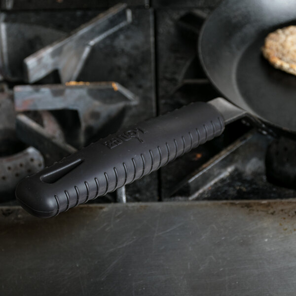 A close-up of a Lodge carbon steel skillet with a black silicone handle cover.