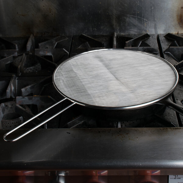 A Lodge splatter screen on a pan on a stove.