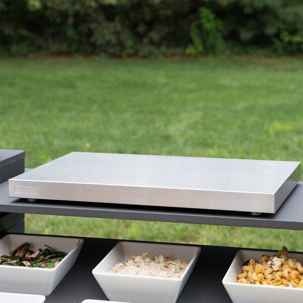 A Vollrath stainless steel cooling plate with food in white bowls on a table.