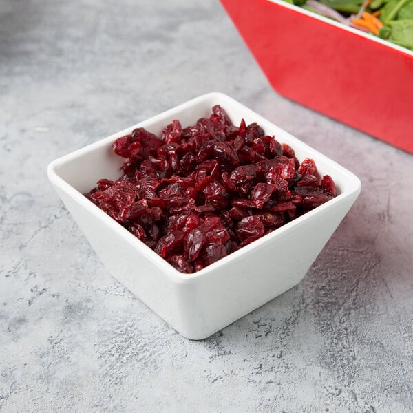 A white Vollrath melamine square bowl filled with cranberry sauce on a counter next to a salad bowl.