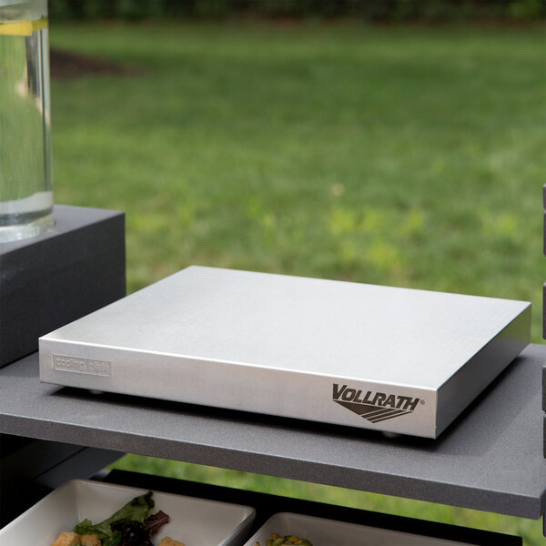 A stainless steel rectangular cooling plate with food on it sitting on a table.