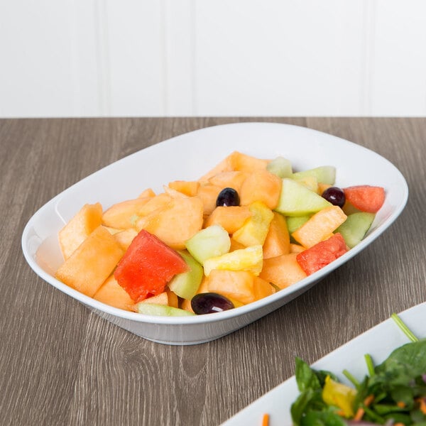 An American Metalcraft oblong melamine bowl filled with fruit salad on a table.