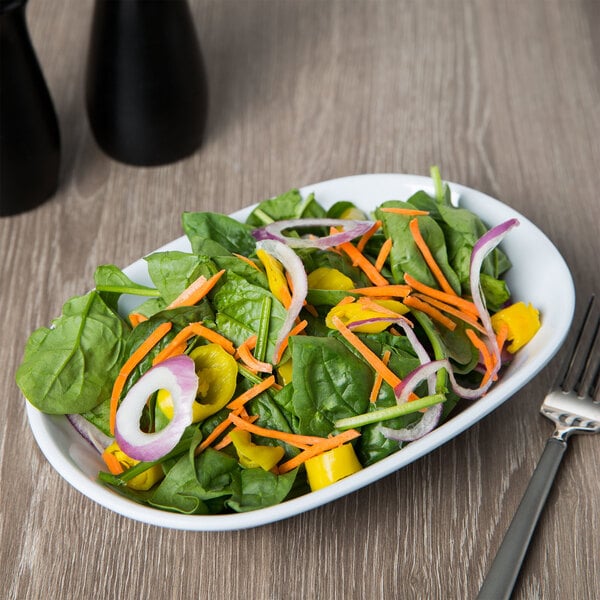 An American Metalcraft oblong melamine bowl filled with salad with carrots, onions, and spinach with a fork on the table.