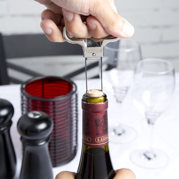A person using a Franmara two-prong cork extractor to open a bottle of wine.
