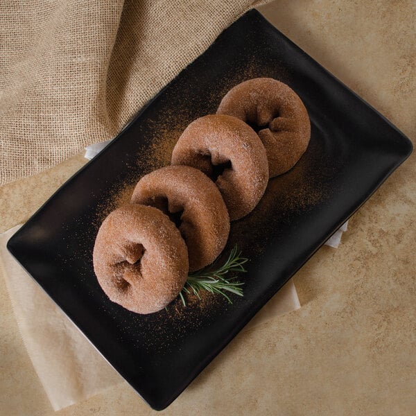 A black rectangular melamine platter with donuts on it.