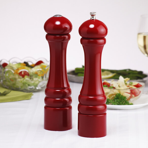 Two Chef Specialties red pepper mills and a salt shaker on a table.
