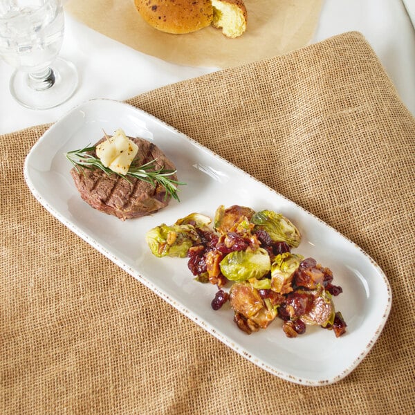 A rectangular melamine platter with a plate of food including meat and vegetables on a table.