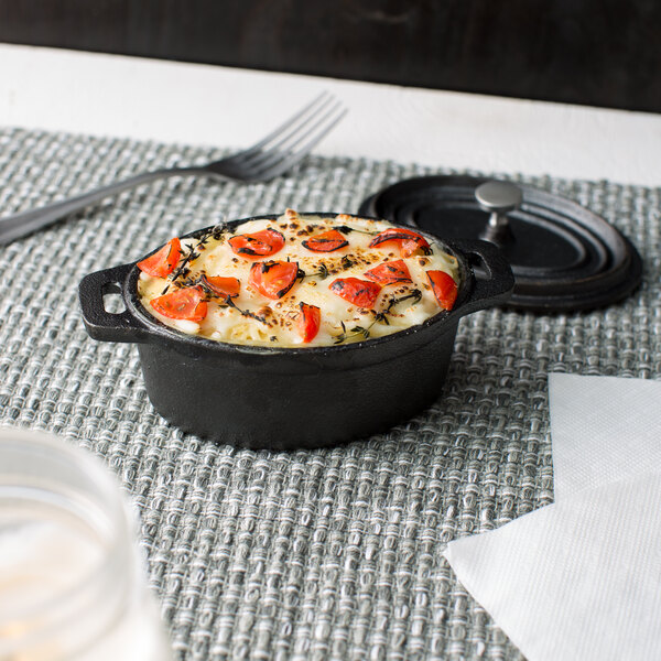 An American Metalcraft mini cast iron oval Dutch oven with food in it on a table.