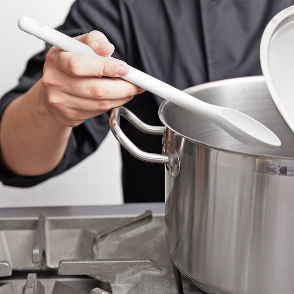 A person using a white Vollrath high heat nylon spoon to stir a pot.