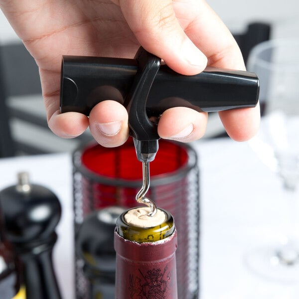A hand using a Franmara Traveler's black corkscrew to open a wine bottle.