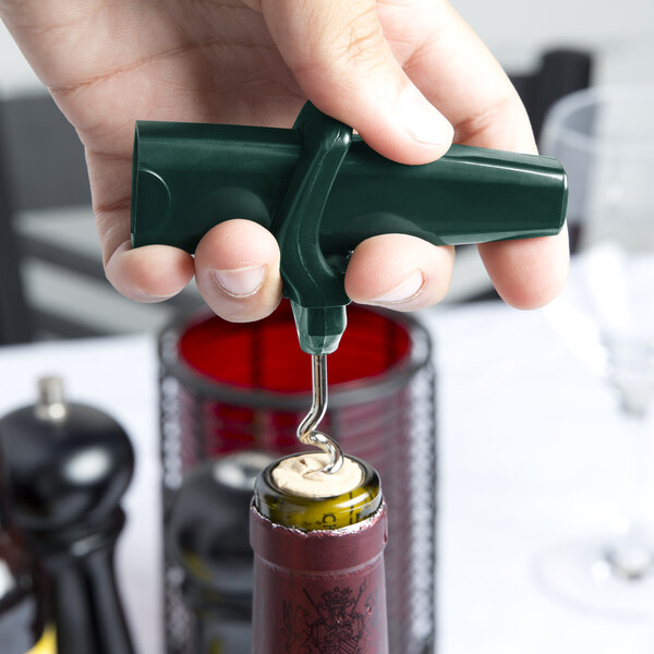 A hand holding a dark green Franmara Traveler's plastic corkscrew and bottle opener over a wine bottle.