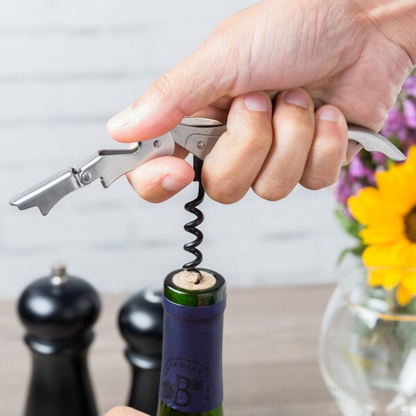A person using a Franmara Duo-Lever corkscrew to open a bottle of wine.