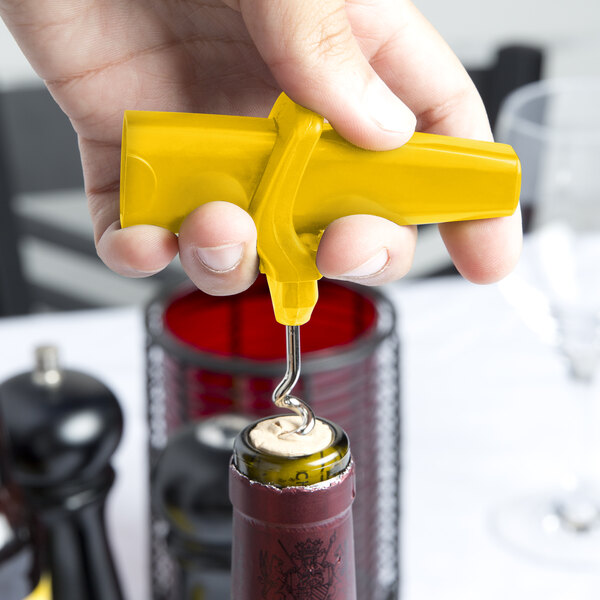 A hand using a yellow Franmara Traveler's corkscrew bottle opener to open a wine bottle.