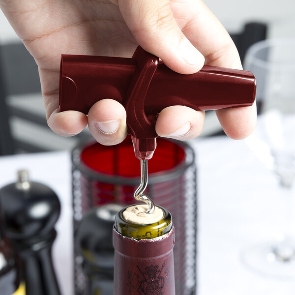 A hand using the Franmara Traveler's Burgundy plastic corkscrew to open a wine bottle.