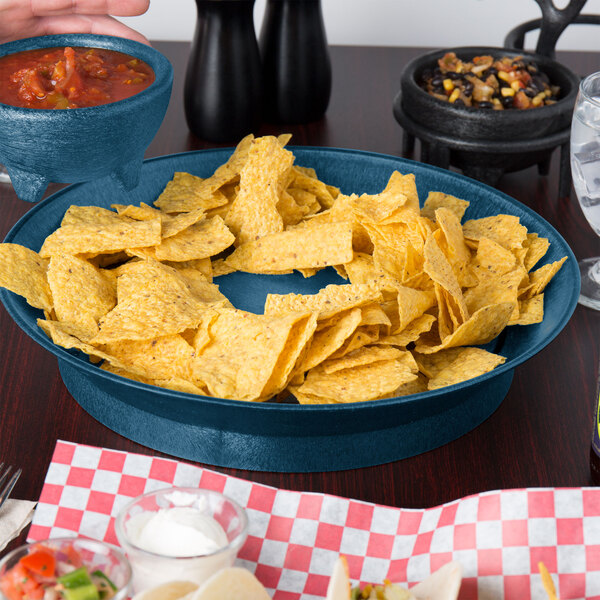 A blue bowl filled with red salsa and a bowl of chips on a table in a Mexican restaurant.