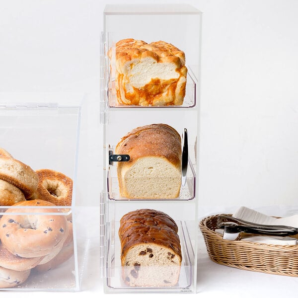 A Cal-Mil clear bread box with three sections holding loaves of bread.