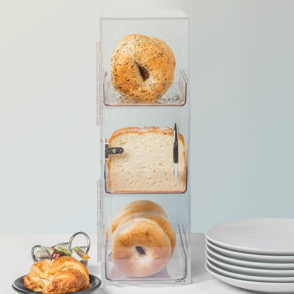 A stack of bread and bagels in a clear container.