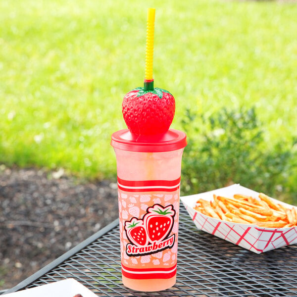 A table with a pink drink in a Sparkle Strawberry Top Souvenir cup with a straw on top.