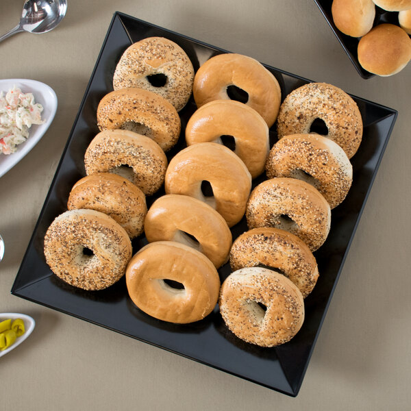 A black square melamine plate with a bagel on it.