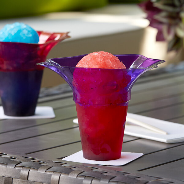 Two tulip-shaped transparent snow cone cups filled with red and purple drinks.