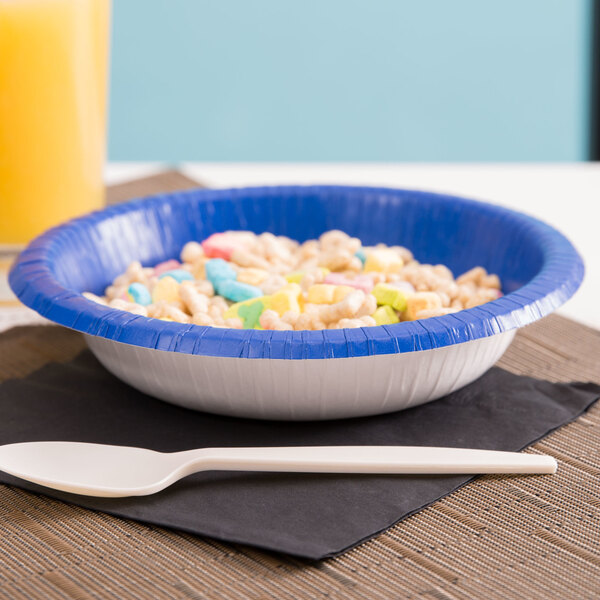 A Creative Converting cobalt blue paper bowl filled with cereal and a spoon.