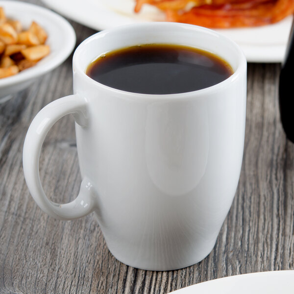 A white Libbey porcelain mug filled with brown liquid on a table.