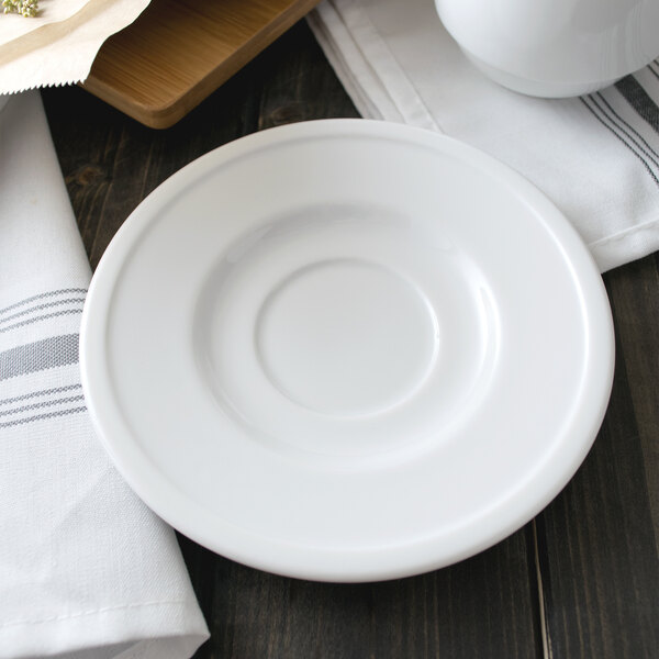 A Libbey alpine white porcelain saucer on a white plate on a wooden surface.