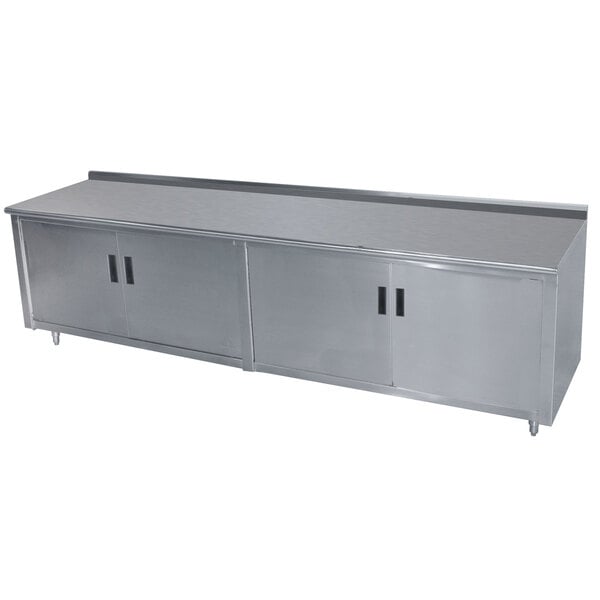 A stainless steel Advance Tabco work table with an enclosed base and hinged doors.